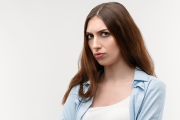Obraz premium Portrait of displeased brunette female with long straight hair, dressed in casual clothes. Isolated on white background.