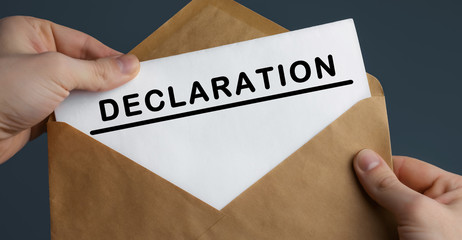 Male hands holding craft envelope with text DECLARATION on blue background