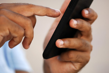 A young man with tanned skin tipping on his his cell phone.