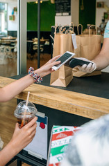 Unrecognizable young woman paying with mobile a take away order