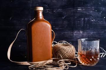 Bottle and glass of whiskey on a dark wood background