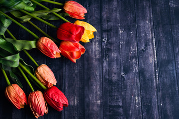 Copy space bouquet of orange and yellow tulips over a rustic wood table top. Flat lay overhead view style.