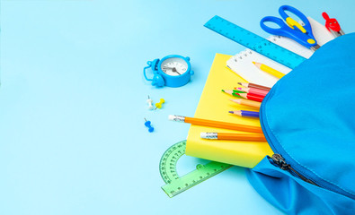 School bag. Backpack with supplies for school on blue background. Copy space for text