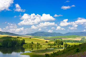 Landscape with hills and lake on a Sunny day, blue sky with clouds. Russia, Altai territory