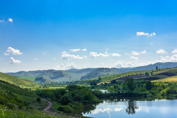 Fototapeta premium Landscape with hills and lake on a Sunny day, blue sky with clouds. Russia, Altai territory