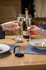 marriage proposal with ring on the table at restaurant couple holding champagne glasses