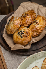 Fresh baked homemade buns with sesame samsa on wooden plate on the table