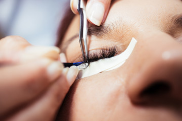 Beautiful middle age woman at eyelash extension procedure. Cosmetics and body care close up shot....