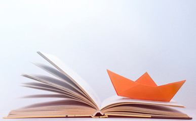 one orange paper boat on a book