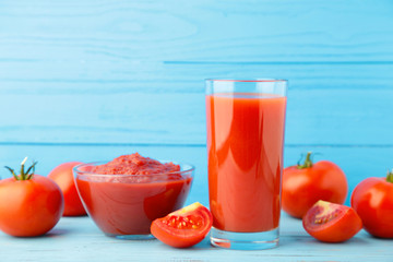 Fresh tomatoes with paste and juice on blue background