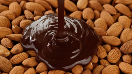 melted chocolate pouring on the almonds top view
