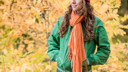 Carefree young woman in autumn park enjoying good warm weather