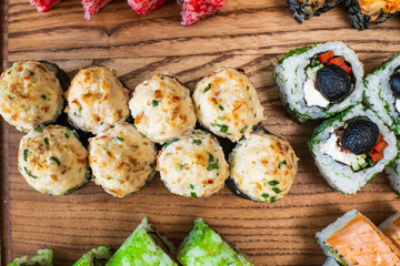 Different types of delicious and juicy sushi and rolls on a wooden board