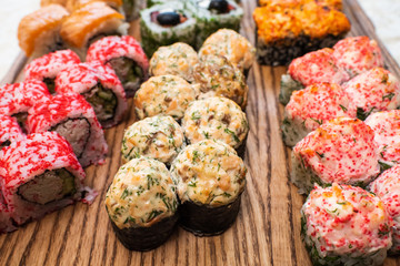 Different types of delicious and juicy sushi and rolls on a wooden board