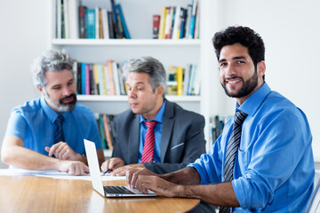 Handsome hipster businessman with beard and older colleagues at office