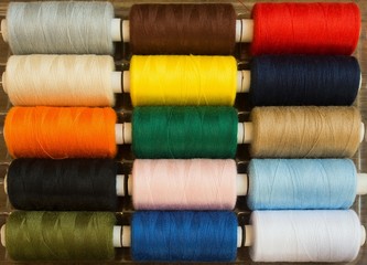 Threads of different colors on spools, regularly arranged in rows