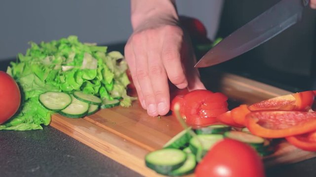 Chef in Blach Uniform is Cutting Vegetables at Home. Cook is Preparing Ingredients for Something Dietary. Healthy Food Concept. Dynamic Closeup Shot