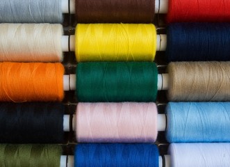Threads of different colors on spools, regularly arranged in rows, 2