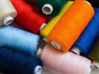 Threads of different colors on spools, irregularly scattered