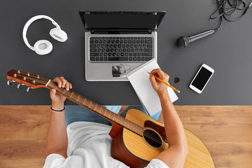 leisure and people concept - young man or musician with laptop computer and guitar writing to music...