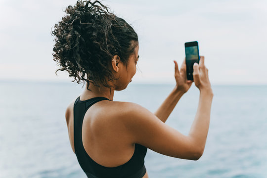 Image of young african american sportswoman taking photo on cellphone