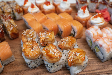 Different types of delicious and juicy sushi and rolls on a wooden board