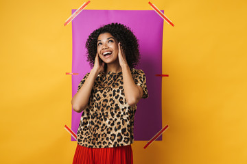 Image of cheerful african american woman smiling and covering her ears