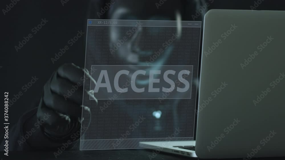 Poster hacker wearing black mask pulls access tab from a laptop