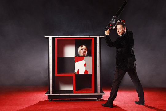 Magician man show trick with box illusion his is saws the girl a chainsaw on the ring in circus