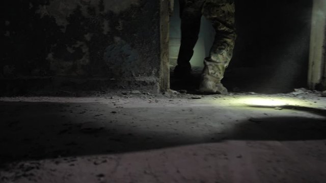 Closeup of special forces fighters' legs in army boots and camouflage pants during storming of captured by terrorists ruined building. Elite team of military men conducting counter-terrorist operation