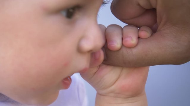 A kid hand holds the father's finger. Raising children in the family, taking care of children. Close-up of a kid's hand. Concept of family planning. A newborn child holds his father's hand.