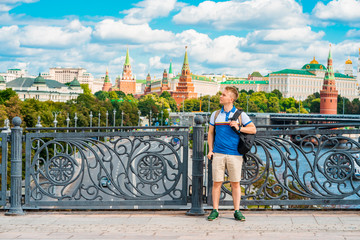 A young male tourist poses on a Sunny day against the background of the Kremlin in Moscow