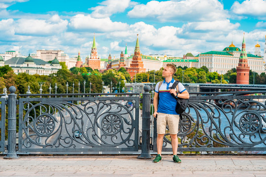 A young male tourist poses on a Sunny day against the background of the Kremlin in Moscow