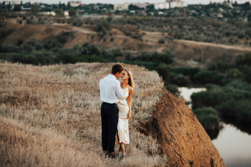 Loving couple dressed in elegant clothes, hug each other tightly. Couple are very happy meeting outdoors.