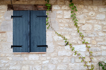 Dark grey window shutters closed in a stone wall surround