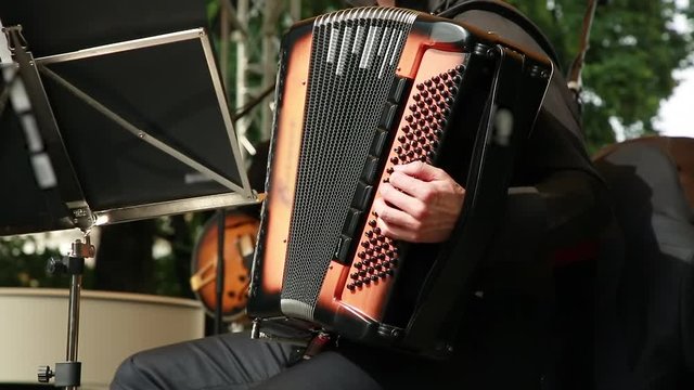 A man plays an accordion on a street stage