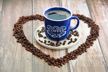 coffee drink in a mug and black coffee beans in a heart shape