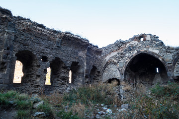 Fototapeta na wymiar Ruins of nameless Russian orthodox church, Kars, Turkey. Remains abandoned, there's no roof. Building has three walls left. Inner courtyard is grown over by wild grass. Located near famous Kars Castle