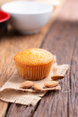 Close up a cup of almond cake against sack fabric on wooden table