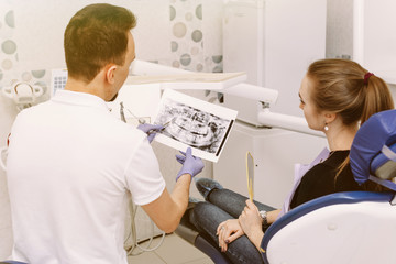 Dentist shows an x-ray of the patient's teeth to a cute woman. Reception at the dentist