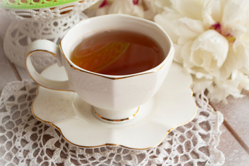 Tea drinking on a summer day. Still life with a cup of tea, white bouquet of peonies on a white lace tablecloth