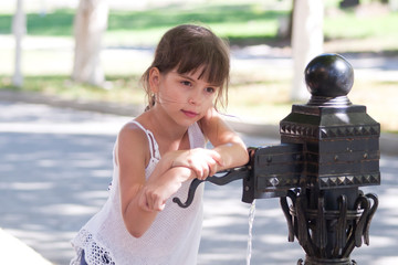 Little girl open the old street free standpipe in summer on blurred background. Outdoors