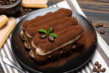 Classic tiramisu dessert on ceramic plate on wooden background