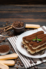 Classic tiramisu dessert and savoiardi cookies on ceramic plate on wooden background