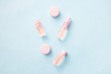 Flat lay of flowers and cosmetics products essential oil: toner, serum, essence, moisturizer and others on blue background, top view, banner. Facial Skin care beauty.