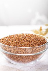 Bowl of raw buckwheat on wooden background. Buckwheat groats (hulled seeds) in bowl.
