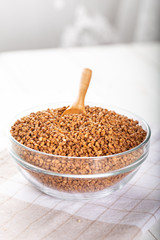 Bowl of raw buckwheat with spoon on wooden background. Buckwheat groats (hulled seeds) in bowl.
