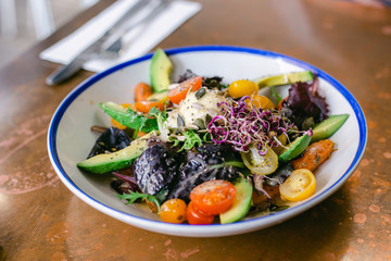 Detox healthy salad with tomatos cherry, micro greens, avocado and carrots. Top view on the table
