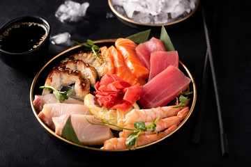 sashimi set of salmon, shrimp, tuna and eel on a black plate - obrazy, fototapety, plakaty