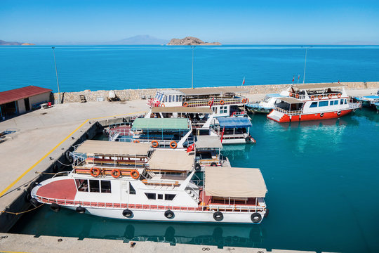 Tourist boats in bay on Van Lake, near Gevaş, Turkey. Akdamar island with Cathedral of Holy Cross are on background. It's popular tourist destination among foreign & local travelers